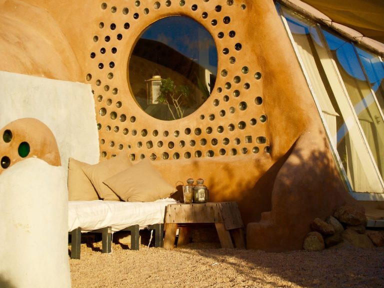 Round window framed by a bottle wall inside the Todos Santos Earthship