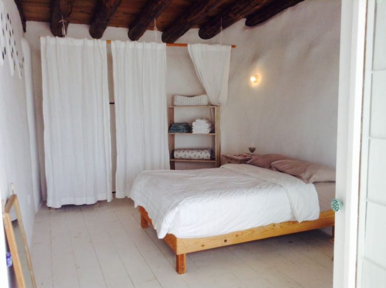 Bedroom with white curtains in the Todos Santos Earthship