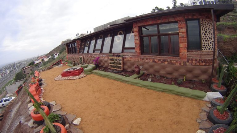 Earthship in Rosarito Beach, Baja California, with a long glazed front and yard