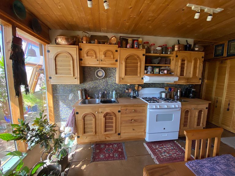 Kitchen with carved pine cabinets in a New Mexico Earthship for sale
