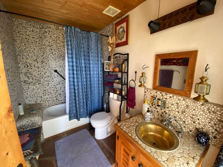 Bathroom with pebble walls and copper sink in a New Mexico Earthship