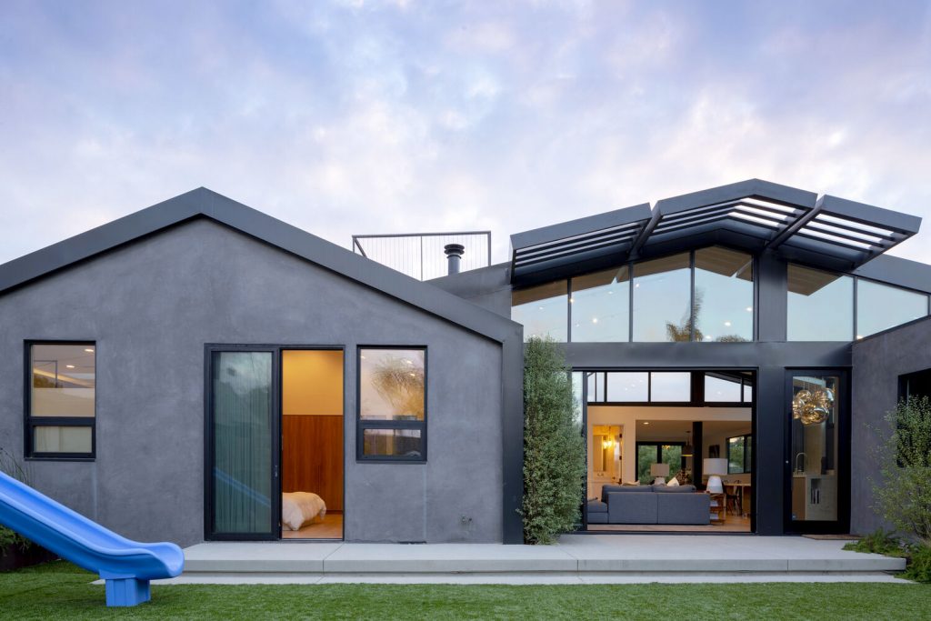 Morningside Remodel rear elevation with standing-seam metal gable roofs at dusk