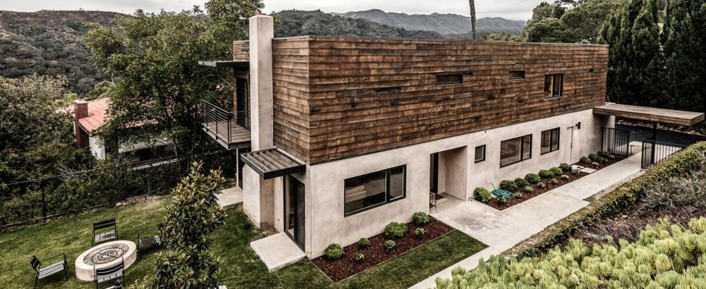 Bayliss Remodel with its wood-clad upper level above a lawn and fire pit