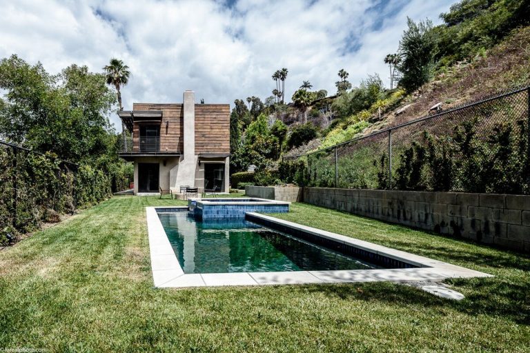 Bayliss Remodel backyard pool and lawn below the wood-clad hillside home