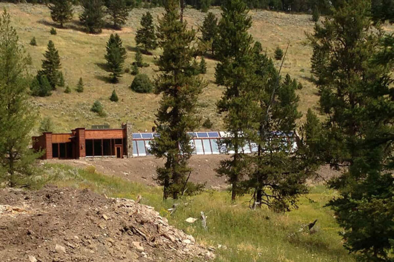 Montana Earthship tucked into a hillside among pine trees