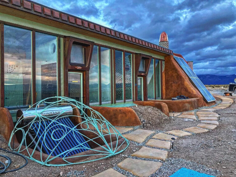 Unity Model Earthship greenhouse front with a flagstone path and a sculpted metal dome