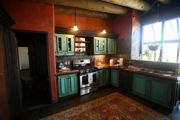 Second kitchen with dark teal cabinets, a gas range and vigas overhead