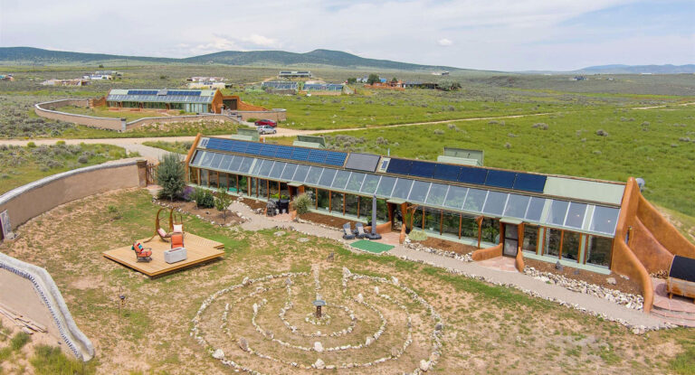 Global Model Earthship from above, with solar panels on the roof and a stone labyrinth in front