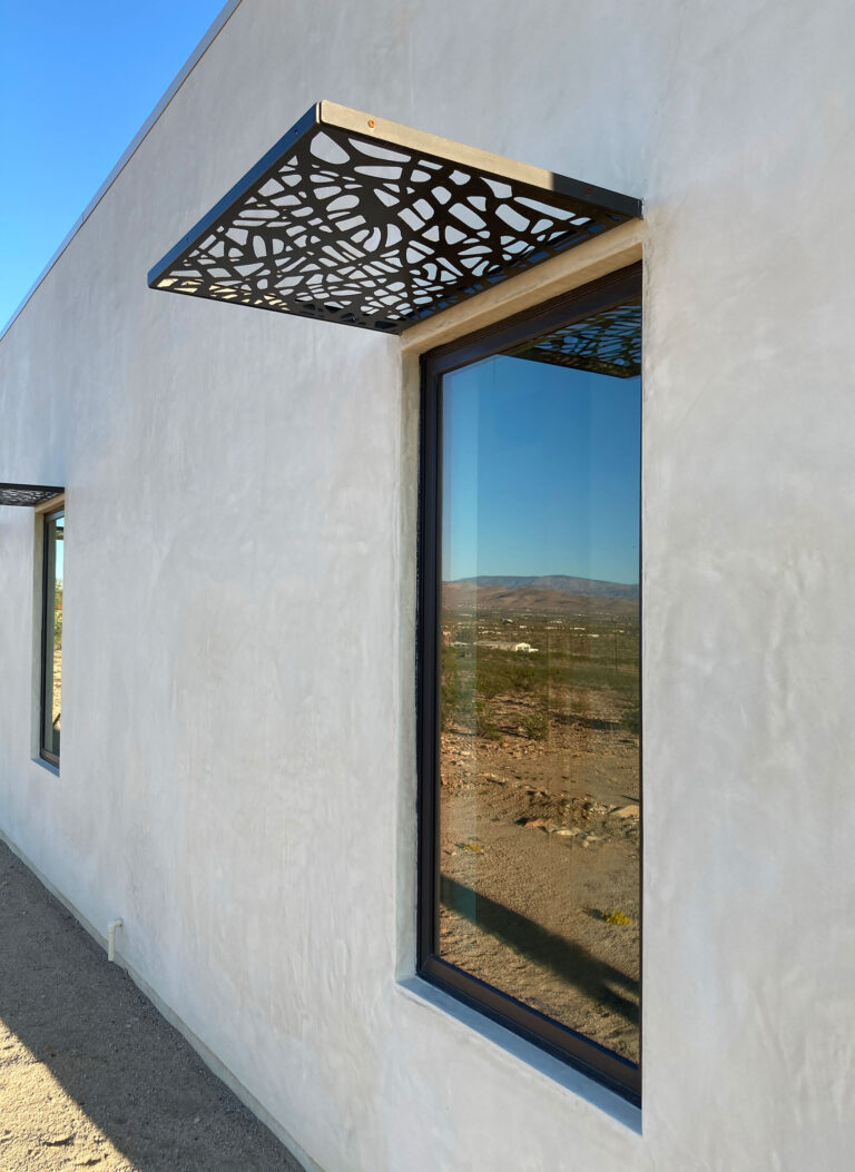 Window with a laser-cut metal shade canopy