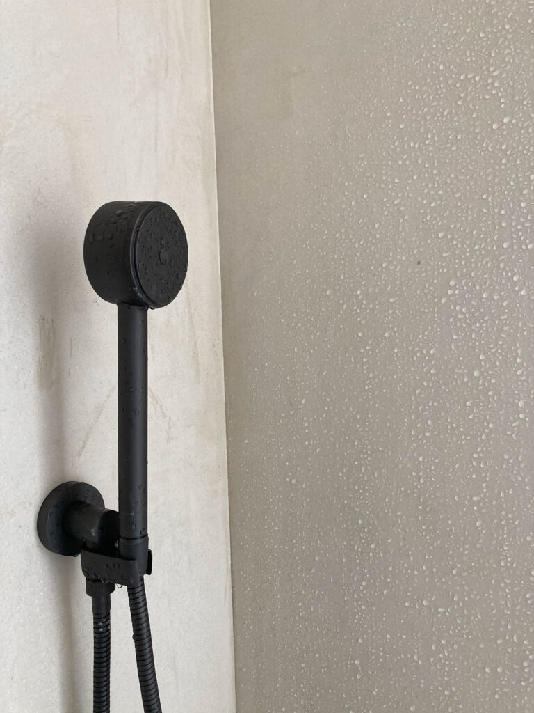 Matte black shower fixture on a plaster wall